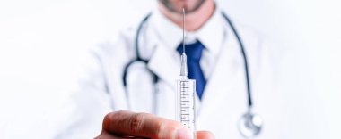 Şırınga iğnesi tıbbi enjeksiyon. Seçici odaklanma, doktorun elinde şırıngayla mavi eldiven tutması. Hastane beyaz doktor önlüğü, steteskop. Kopya alanı olan grip aşısı şırıngası