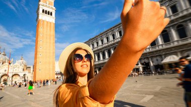 Seyahat etmenleri Venedik adasını etkiliyor. Avrupa 'da Venezia şehrinde boyama evi. Venice San Marco Meydanı 'nda akıllı telefonlu blogcu kız. Seyahat ve serbest çalışma, modern yaşam tarzı.