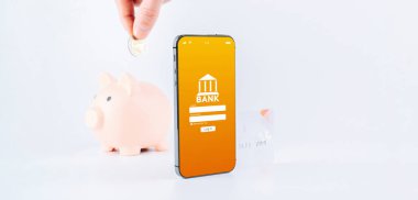 Mobil bankacılık. İnternet banka başvurusu olan akıllı bir telefon. Beyaz arka planda banka kartı olan domuz kumbarası. Para tasarrufu iş kavramı
