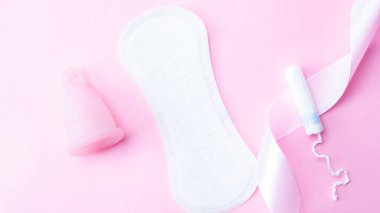 Adet bardağı, tampon, hijyenik koruma için kadın bardağı. Adet bardaklı pembe kurdele. Adet dönemi kadınsı. Sıfır atık kavramı, çevre dostu yaşam tarzı, düşük bayrak tüketimi