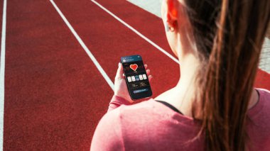 Sağlık uygulaması. Spor salonu ya da spor salonu mobil uygulaması olan akıllı telefon ekranı. Evde tutulan kadın çevrimiçi egzersiz uygulaması