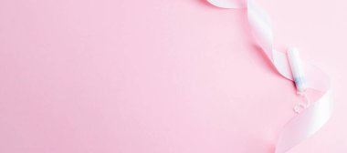 Adet öncesi tampon, kadın hijyeni. Pembe arka planda adet tamponu olan pembe kurdele. Adet dönemi kadınsı. Hijyen konsepti. Sağlık sigortası jinekolojik afişi