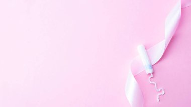 Tampon kadın hijyen. Pembe arka planda adet tamponu olan pembe kurdele. Adet dönemi kadınsı. Kritik günlerde kadınlar için yumuşak ihale koruması