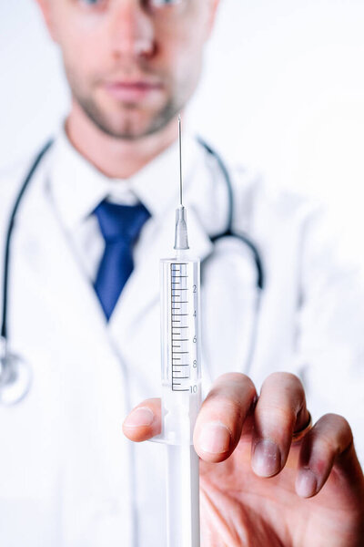 Syringe needle medical injection. Selective focus, doctor hand in blue gloves holding syringe with needle. Hospital white doctor gown, stethoscope. Syringe with flu vaccine with copy space