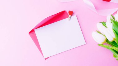 Anneler günü hediyesi. Bahar beyazı lale çiçeği, pembe arka planda kırmızı kurdeleli hediye. Sevgililer günü, doğum günü, kadınlar veya düğün günü konsepti