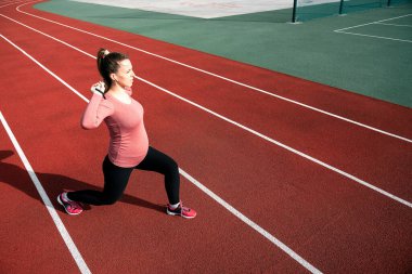 Hamilelik egzersizi. Hamile kadın yoga sporu antrenmanı yapıyor. Dışarıda doğum öncesi sağlıklı spor salonu var. Hamilelik koşusu