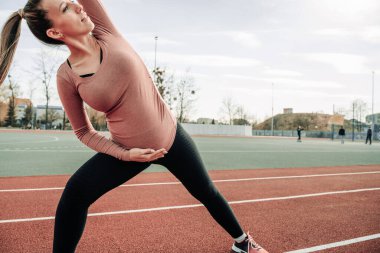 Hamilelik eğitimi. Hamile kadın yoga sporu antrenmanı yapıyor. Dışarıda doğum öncesi sağlıklı spor salonu var. Doğum öncesi egzersizleri..