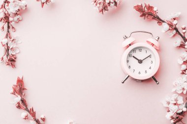 Bahar çiçeği. Çiçekler ve çiçekli pembe arka planda çalar saat. Yumuşak odaklı, çiçek açan kayısı makrosu dalları. Kopya alanı olan Paskalya tebrik kartları için. İlkbahar
