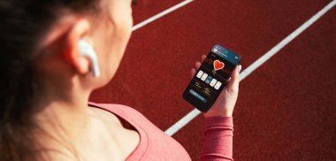 Jimnastik uygulaması. Spor salonlu akıllı telefon ekranı ya da spor amaçlı mobil sağlık uygulaması. Kadın içeride eğitim için uygulama tutuyor.