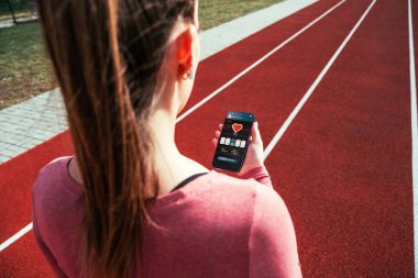 Jimnastik uygulaması. Spor salonlu akıllı telefon ekranı ya da spor amaçlı mobil sağlık uygulaması. Kadın içeride eğitim için uygulama tutuyor.
