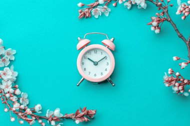 Sakura çiçeği, ilkbahar çiçeği ve mavi arka planda çalar saati olan Nisan çiçekleri. 8 Mart bayrağı, mesaj için yeri olan mutlu Paskalyalar. Kopya alanı olan tebrik kartları için ilkbahar kavramı