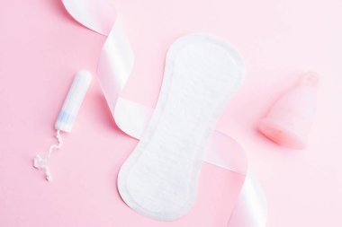 Adet bardağı, tampon, hijyenik koruma için kadın bardağı. Adet bardaklı pembe kurdele. Adet dönemi kadınsı. Sıfır atık kavramı, çevre dostu yaşam tarzı, düşük bayrak tüketimi