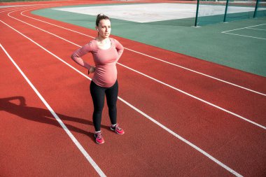 Hamilelik egzersizi. Hamile kadın yoga sporu antrenmanı yapıyor. Dışarıda doğum öncesi sağlıklı spor salonu var. Hamilelik koşusu