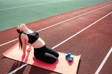 Hamilelik eğitimi. Hamile kadın yoga sporu antrenmanı yapıyor. Dışarıda doğum öncesi sağlıklı spor salonu var. Doğum öncesi egzersizleri.