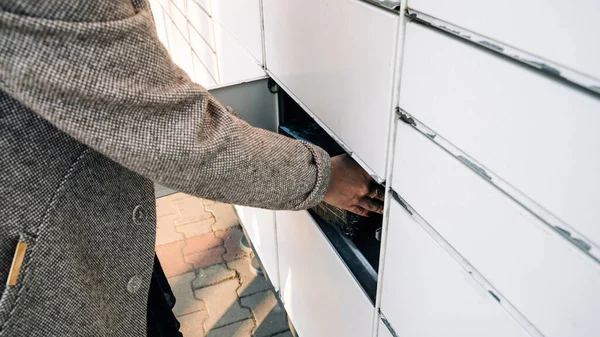 Paket geldi. Posta otomat terminalinde kurye kutusu kadınların elinde. self servis posta terminali ve paket teslimatı kavramı