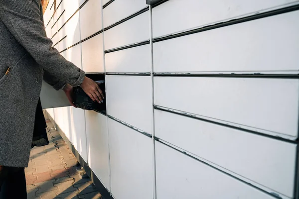 Post locker. Delivery automat terminal and hands with parcel courier box. Parcel delivery, pickup point with lockers, hand with parcel, contactless pack delivery