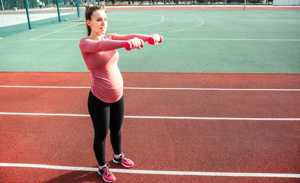 Hamilelik egzersizi. Hamile kadın yoga sporu antrenmanı yapıyor. Dışarıda doğum öncesi sağlıklı spor salonu var. Hamilelik koşusu