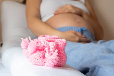 Bebek ayakkabılı hamile kadın. Güzel hamile kadın pembe bebek ayakkabıları tutuyor. Hamilelik kavramı, annelik, bebek doğumu beklentisi