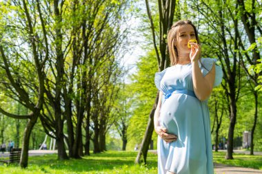 Hamile kadın yürüyüşü. Hamile doğa yürüyüşü. Yaz parkında mutlu annelik anneleri. Bebek göbeği. Hamilelik aktivitesi.