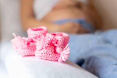 Hamilelik ayakkabıları bebeğim. Hamile anne kız bebek için küçük bir çocuk ayakkabısı tutuyor. Gebelik, hamilelik, doğum. Güzel anne bebeği bekliyor.