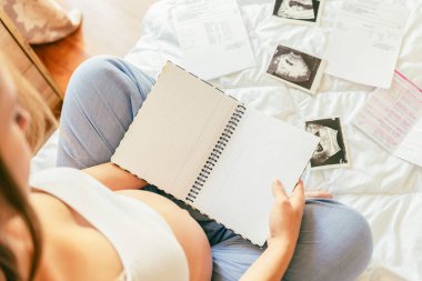 Bebek listesi hamile kadın. Genç hamile anne not defteri tutuyor. Hamile kadın bebek için kontrol listesi yazıyor. Annelik kavramı, beklenti
