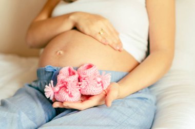 Çocukların ayakkabıları hamile kadın. Güzel hamile kadın pembe bebek ayakkabıları tutuyor. Bebeği bekliyorum. Hamilelik, hamilelik konsepti