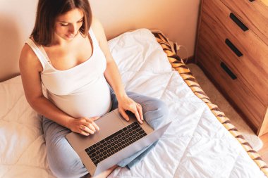 Hamilelik bilgisayar uygulaması. Elinde dijital laptop tutan hamile bir kadın. Taşınabilir hamilelik çevrimiçi annelik not defteri uygulaması. Gebelik, gebelik, doğum