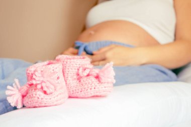 Hamilelik ayakkabıları bebeğim. Hamile anne kız bebek için küçük bir çocuk ayakkabısı tutuyor. Gebelik, hamilelik, doğum. Güzel anne bebeği bekliyor.