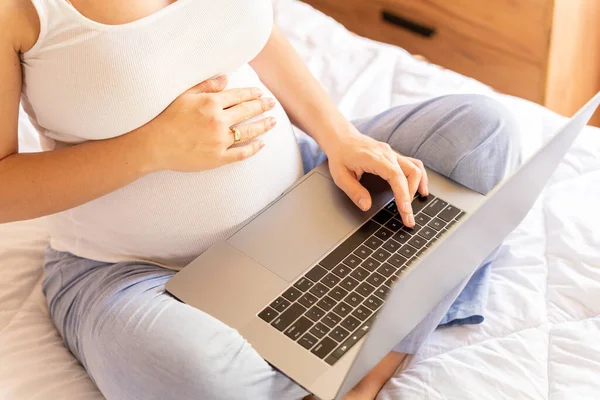 Pregnancy digital laptop. Pregnant woman holding digital computer. Mobile pregnancy online maternity notebook application. Concept of pregnancy, maternity, expectation for baby birth