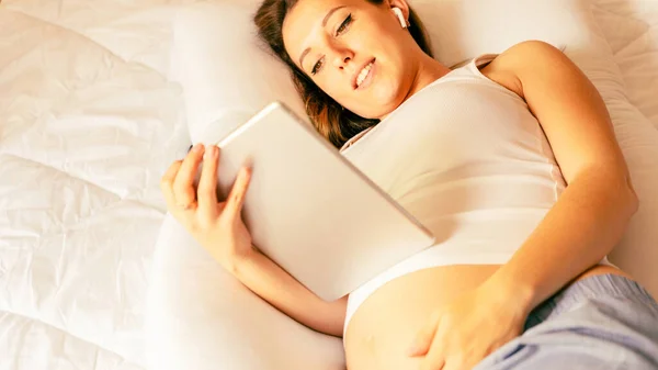Pregnant tablet health app. Pregnant woman holding digital tablet. Mobile pregnancy online maternity application. Concept of pregnancy, maternity, expectation for baby birth