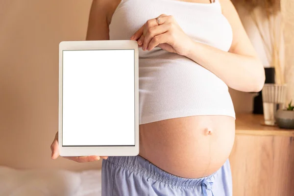 Pregnancy digital tablet mockup. Pregnant woman holding smart tablet. Mobile pregnancy online maternity application mock up. Concept of pregnancy, maternity, expectation for baby birth
