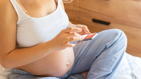 Pregnancy health app. Pregnant woman holding smartphone. Mobile pregnancy online maternity application. Concept of pregnancy, maternity, expectation for baby birth