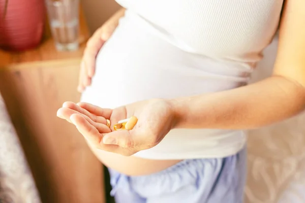 Maternal supplements pill. Happy smiling woman taking pill with supplement vitamin Omega 3. Pregnancy, medicine health care concept