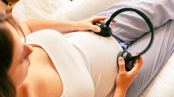 Pregnant woman music listen. Cheerful pregnancy girl relaxing listening music in headphones. Mother belly listen headphones sound. Pregnancy, medicine health care and people concept