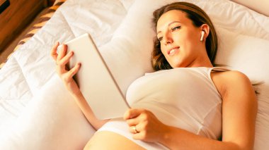 Hamilelik dijital tableti. Elinde dijital tablet olan hamile bir kadın. Taşınabilir hamilelik çevrimiçi annelik başvurusu. Hamilelik kavramı, annelik, bebek doğumu beklentisi