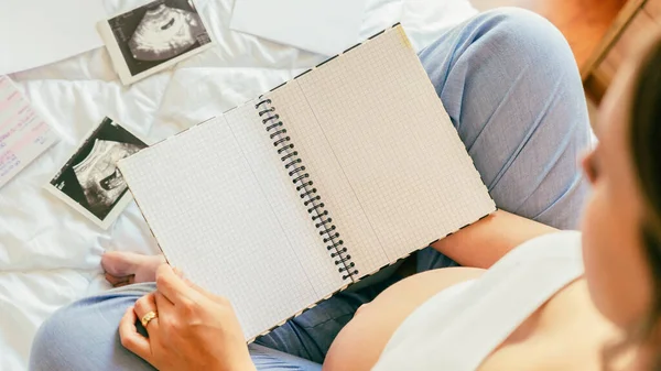 Pregnancy list woman writing. Beautiful pregnant woman writing check list. Happy pregnancy lady holding notepad. Concept maternity, childbirth