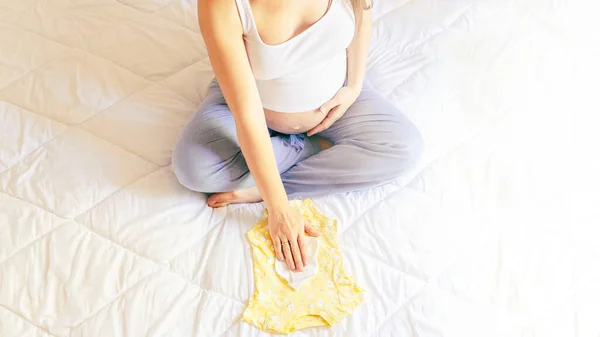 Babykleidung Für Frauen Glückliche Junge Schwangere Mutter Mit Gelber Babykleidung — Stockfoto