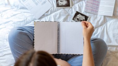 Hamilelik listesi yazan kadınlar. Güzel hamile kadın kontrol listesi yazıyor. Elinde not defteri tutan mutlu hamile kadın. Gebelik kavramı, doğum