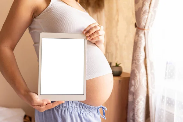Pregnancy digital tablet mockup. Pregnant woman holding smart tablet. Mobile pregnancy online maternity application mock up. Concept of pregnancy, maternity, expectation for baby birth