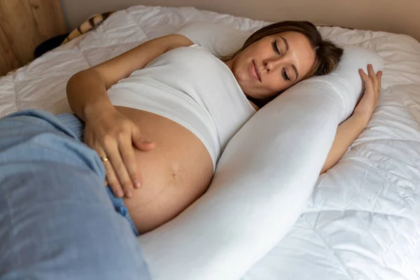 Pregnant sleep pillow woman. Young pregnancy mother sleep with pregnant belly support pillow. Pregnancy, medicine, pharmaceutics, health care and people concept
