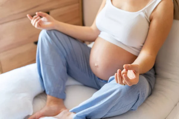 Healthy pregnancy meditation. Beautiful pregnant woman meditating while sitting in lotus position. Health yoga home sport. Pregnancy, maternity, healthcare concept