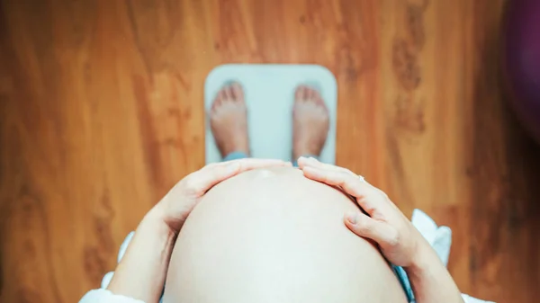 Pregnant weights woman belly. Happy pregnancy woman standing on weight scales. Pregnancy, medicine health care concept