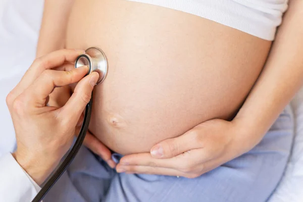 Pregnant consult doctor. Medical clinic for pregnancy consultant. Doctor examining pregnancy woman belly holding stethoscope. Concept of pregnancy, maternity, expectation for baby birth