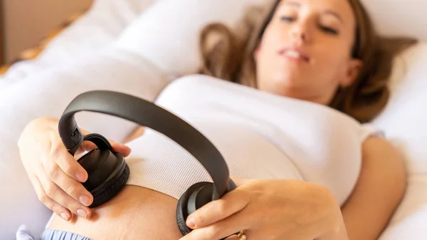 Pregnancy music woman listen. Pregnant woman listening to music. Mother belly listen headphones sound. Concept of pregnancy, maternity, expectation for baby birth