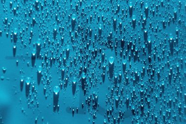 Su mavi arkaplanı düşürür. Damlacık yağmur dokusu sıçratıyor. Su sıçratma deseni. Seçici odak