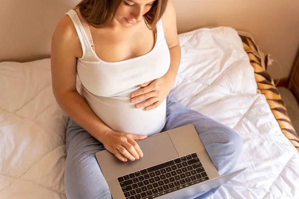 Woman holding computer. Mobile pregnancy online maternity notebook application. Pregnant mother using digital laptop. Pregnancy, medicine, pharmaceutics, health care and people concept