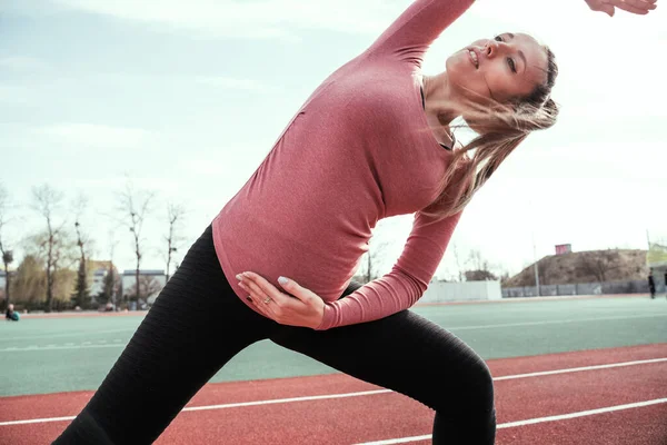 Hamilelik egzersizi. Hamile kadın yoga sporu antrenmanı yapıyor. Dışarıda doğum öncesi sağlıklı spor salonu var. Hamilelik koşusu