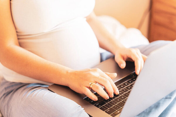 Pregnant computer. Pregnant woman holding digital laptop. Mobile pregnancy online maternity application. Concept of pregnancy, maternity, expectation for baby birth