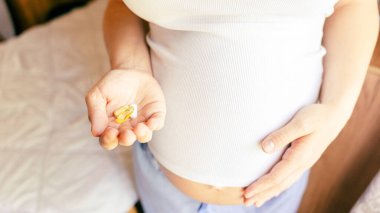 Doğum öncesi vitamin hapı. Mutlu gülümseyen kadın Omega 3 vitamini ile hap alıyor. D vitamini, E vitamini, Balık yağı kapsülleri