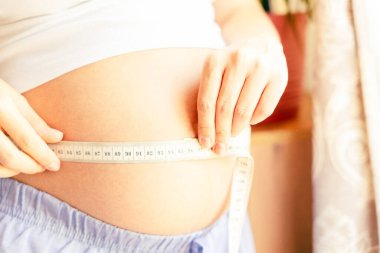 Hamile karın ölçüsü. Göbeğinde bant olan mutlu, güzel, hamile bir kadın. Hamilelik, ilaç sağlık konsepti